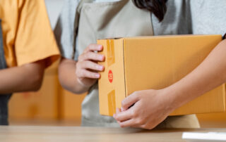 A small shipping box being held by a mail carrier.