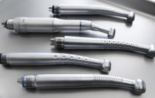 Five handpieces placed on a silver tray for inspection by the dentist.