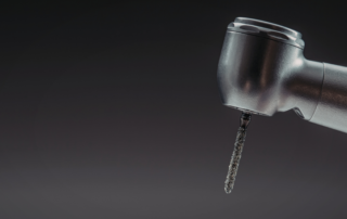 An extreme close-up image of the head of a dental handpiece with a bit inserted.